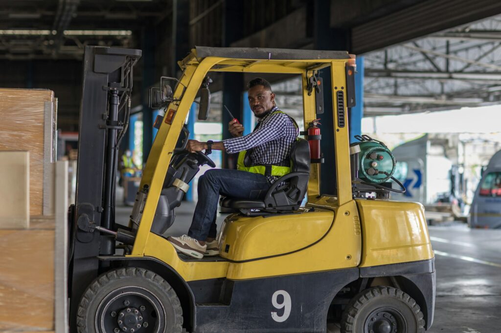 Man worker at forklift driver happy working in industry factory logistic ship.