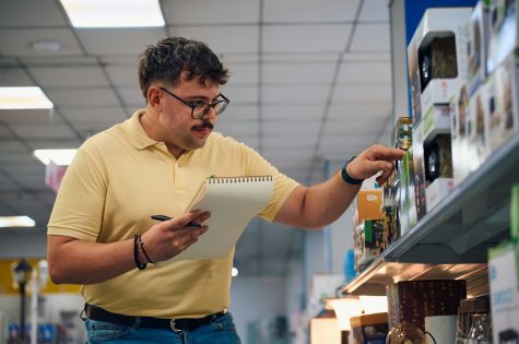 Employee reviewing merchandise on a retail shelf during the afternoon at a store