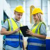 Engineer controlling industrial machine working with assistant worker checking first for labour